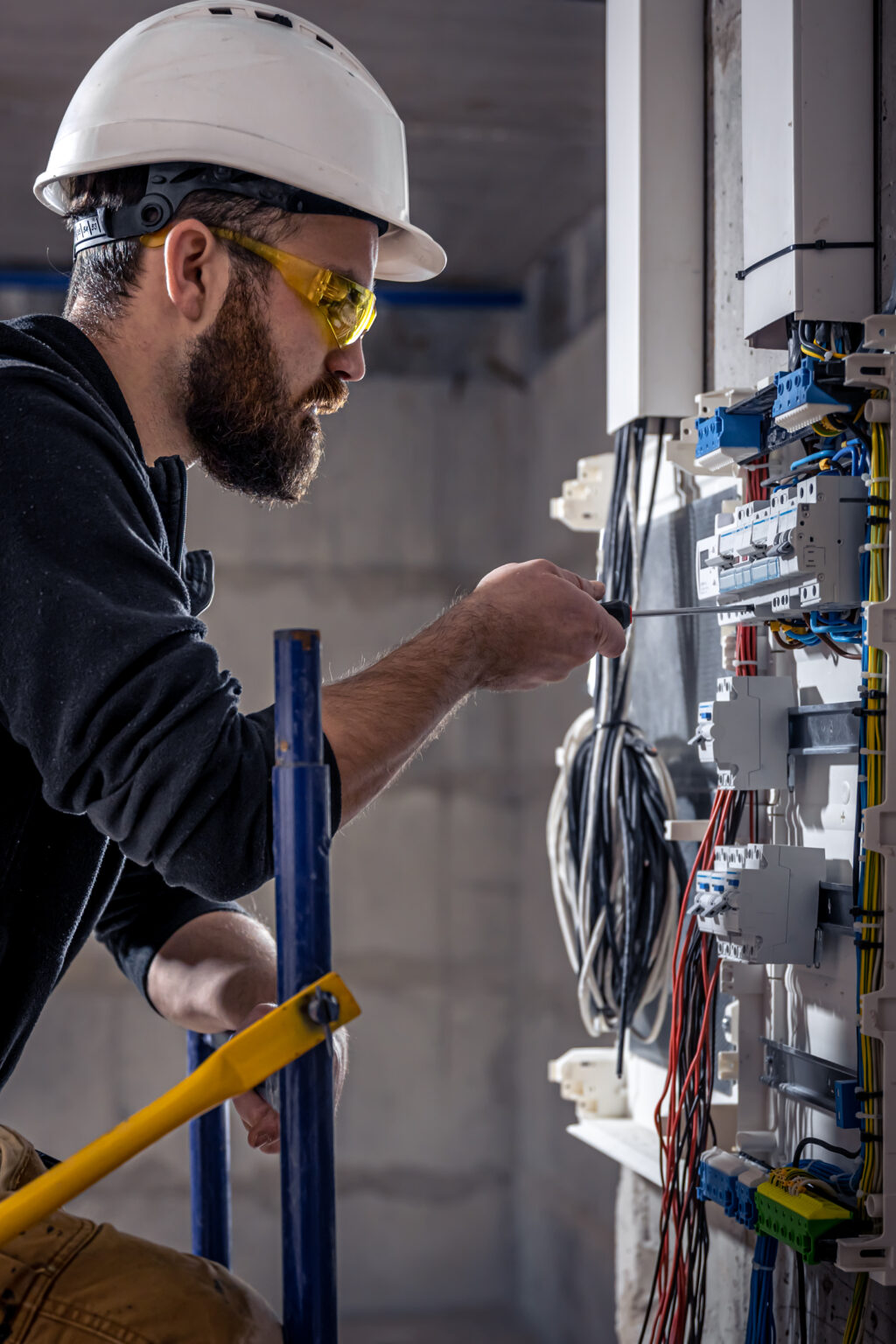 a male electrician works in a switchboard with an electrical connecting cable.